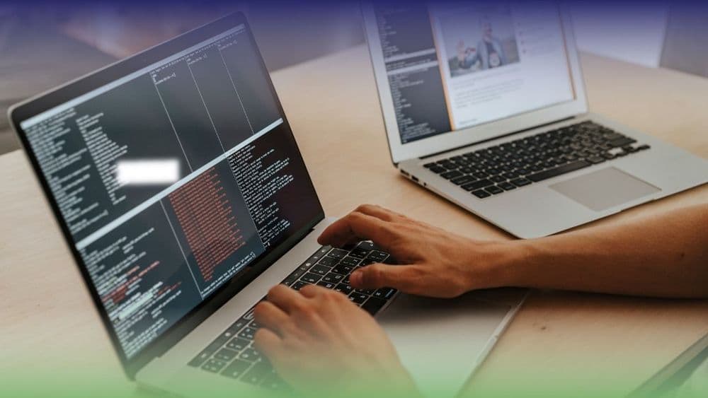 Hands typing on a laptop - code